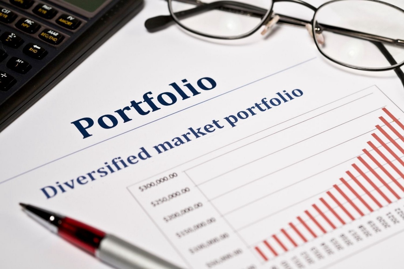 Image of a portfolio with eye glasses and a writing pen on a desk.