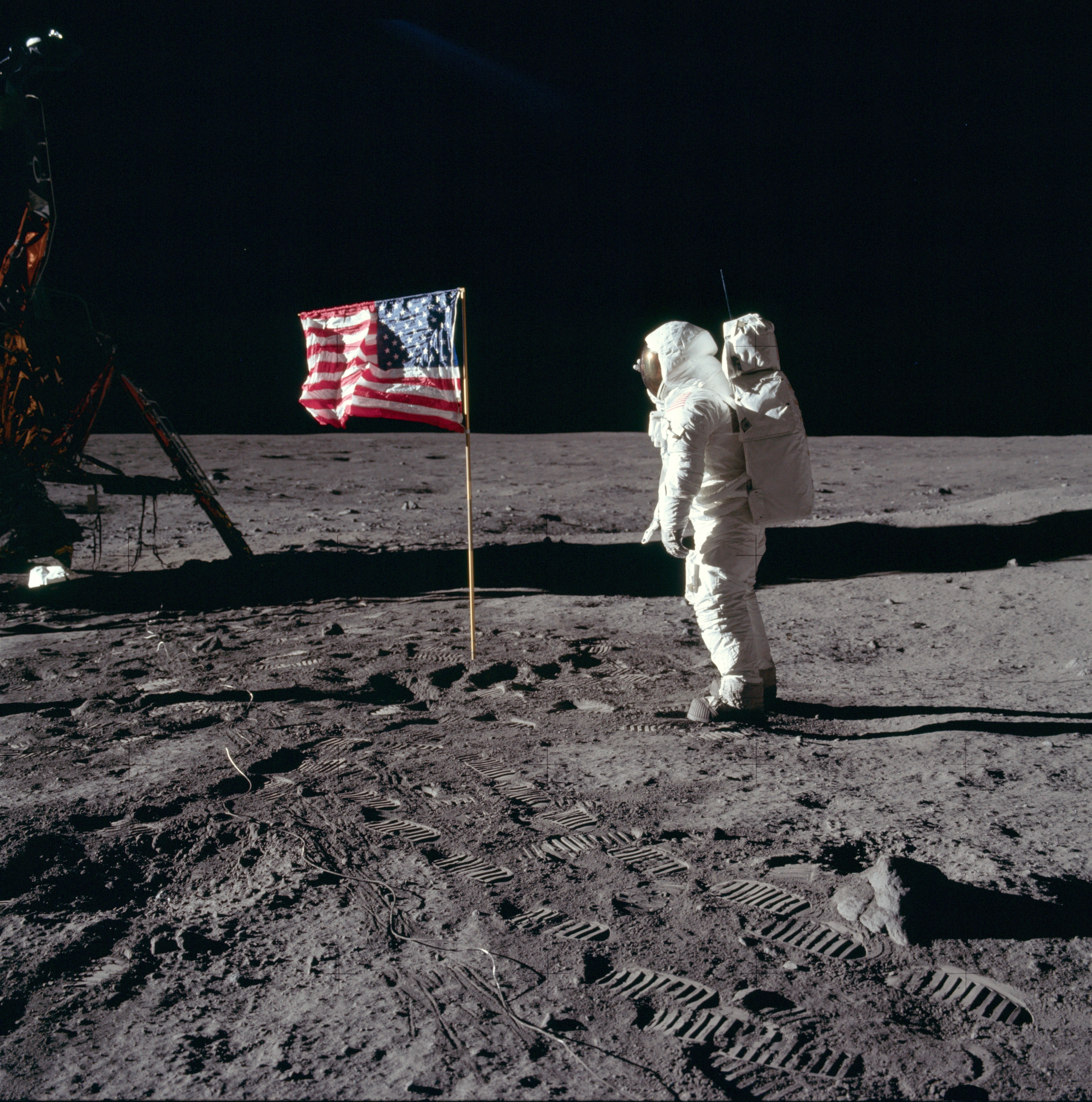 Buzz Aldrin in een ruimtepak op het oppervlak van de maan naast de Amerikaanse vlag.