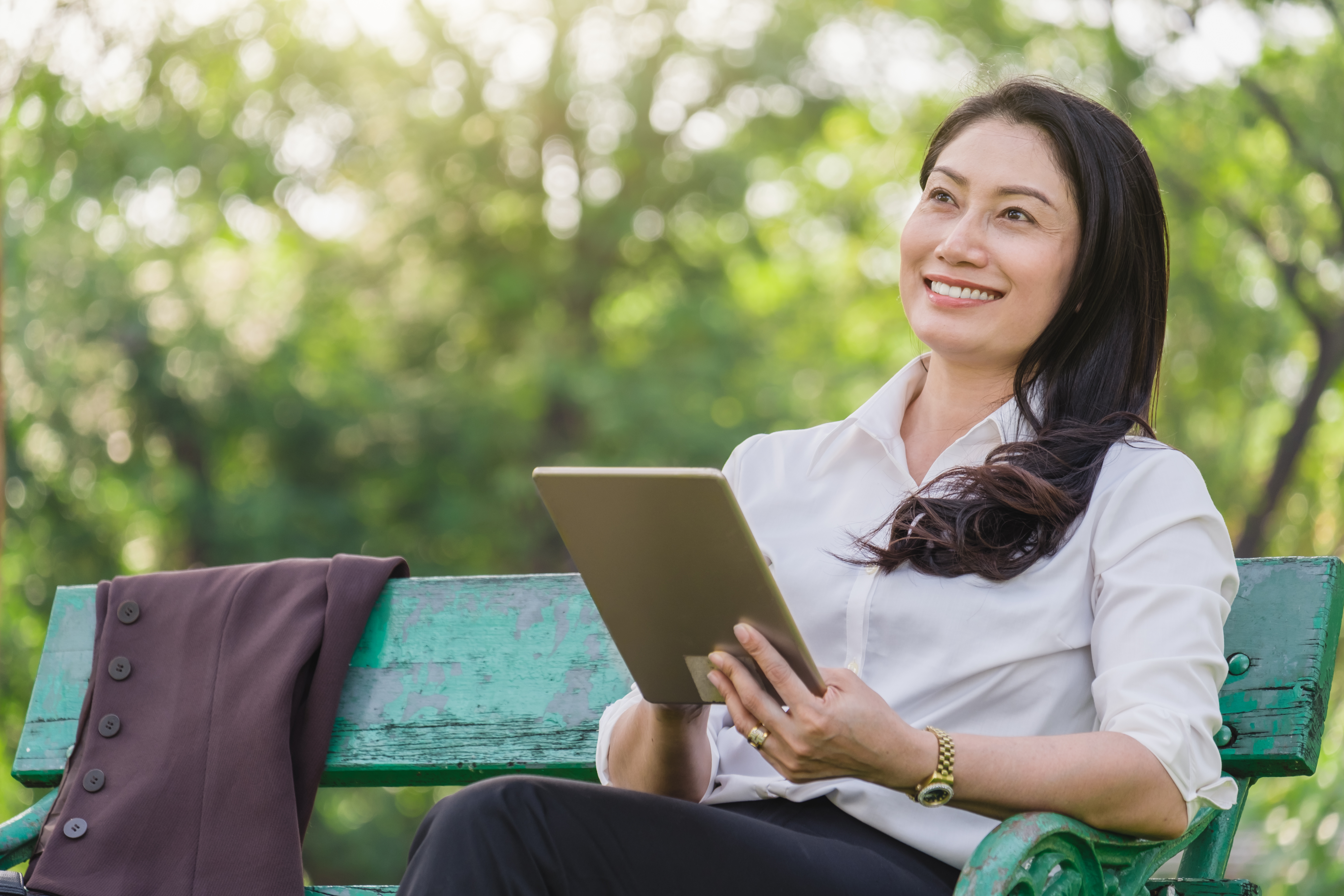 Businesswoman working from tablet outdoors in a park