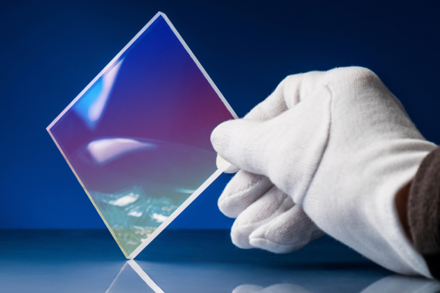 White-gloved hand holds a square of milky-looking glass