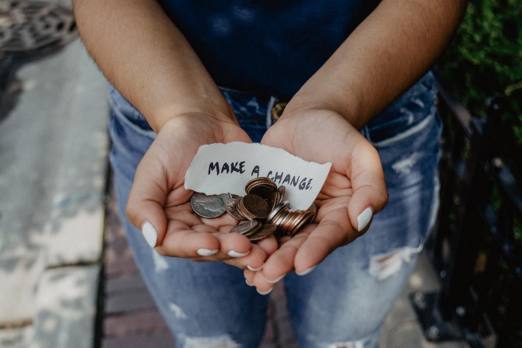 person showing both hands with make a change note and coins.How to start a fundraiser 