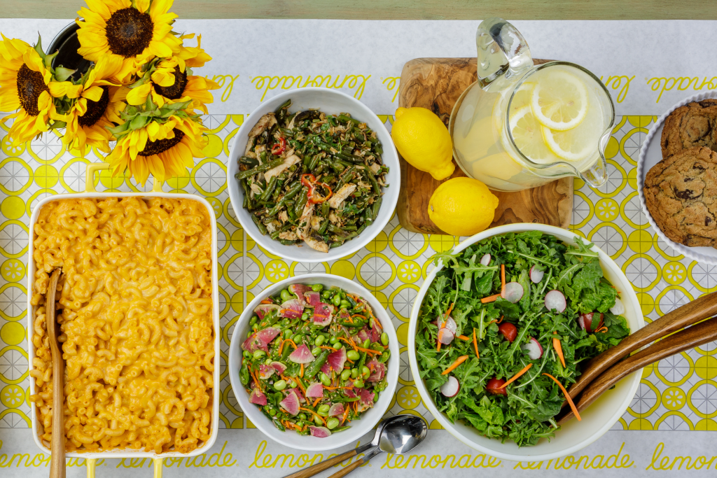 a table with three salads, mac and cheese, lemonade, lemons, cookies and sunflower. Fundraising Restaurants In San Diego mac and cheese, lemonade, lemons, cookies and sunflower. 