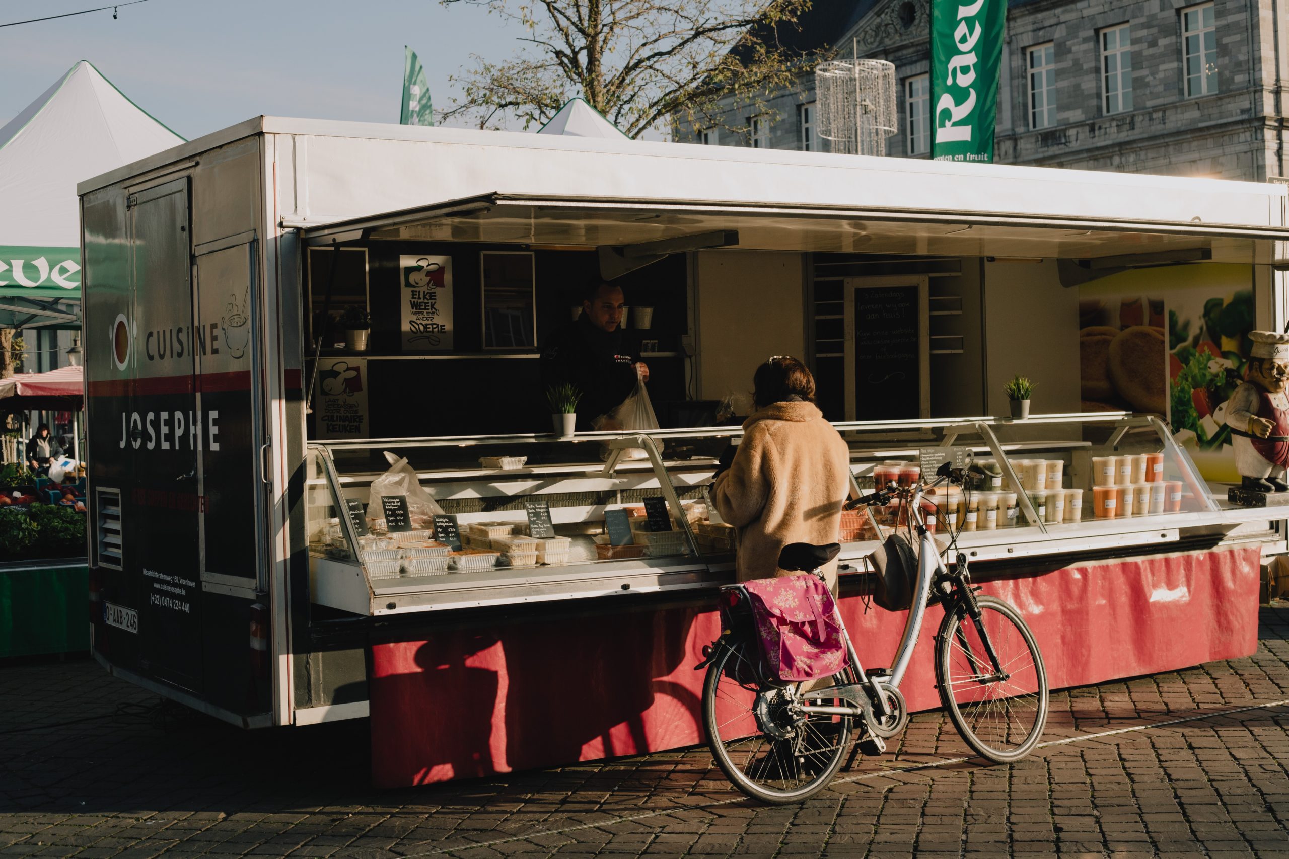 Outdoor food stand with girl on her bicycle making a purchase