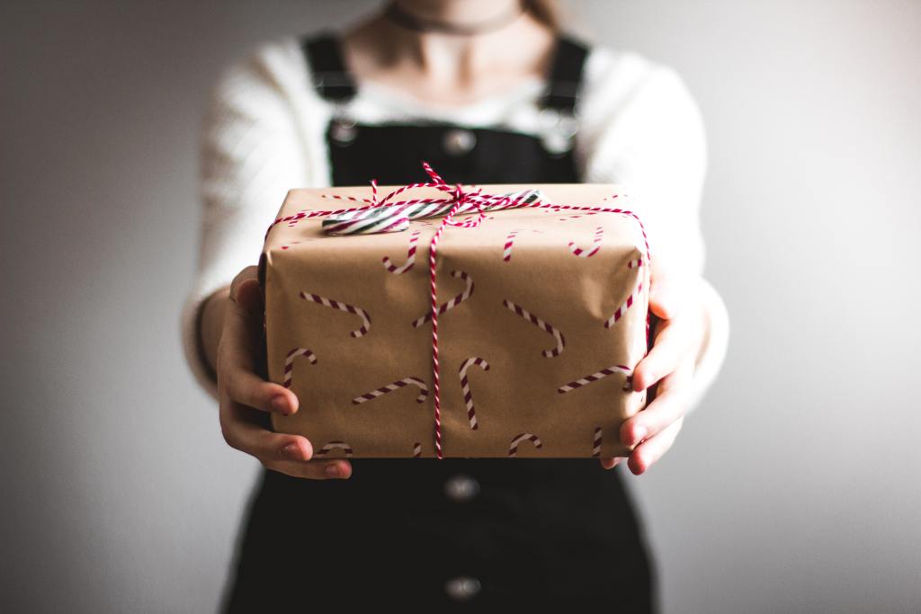 भूरा उपहार बॉक्स दिखाने वाला व्यक्ति। मासिक देने का कार्यक्रम कैसे बनाएं