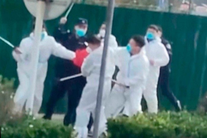 Petugas keamanan menyerang seorang pengunjuk rasa dengan pentungan di kompleks pabrik yang dioperasikan oleh Foxconn di Zhengzhou, Henan, Tiongkok, pada November 2022