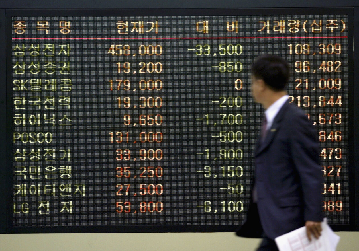 一名韩国男子走过韩国首尔的股指板 | 韩国将建立加密代币证券市场 | 韩国加密货币、韩国证券市场、证券代币