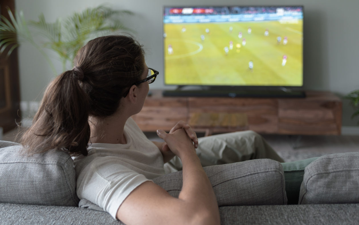 امرأة تشاهد كرة القدم على شاشة التلفزيون