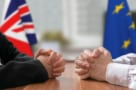 صورة لزوجين من الأيدي على طاولة لوحية عليها علم الاتحاد الأوروبي وعلم المملكة المتحدة
