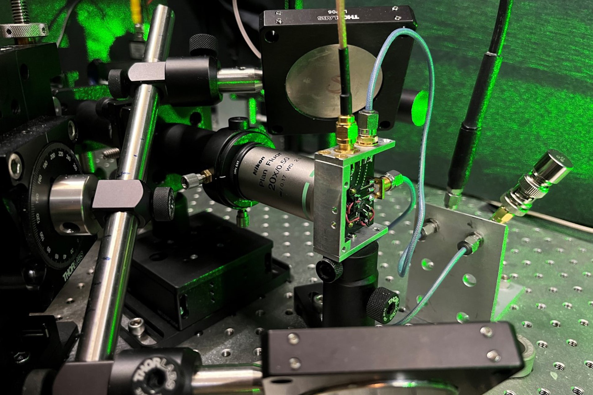 ein Metallapparat mit grünem Laserlicht im Hintergrund