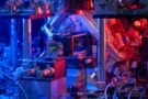 Foto av et vakuumkammer, optiske fibre og andre komponenter, badet i blått og rødt lys