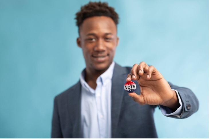 man holding a vote pin