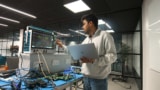 En man i en hoodie arbetar med en bärbar dator och ett kvantsystem