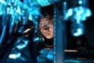 Foto einer Person, die ein Mikroskop benutzt, getaucht in blaues Licht