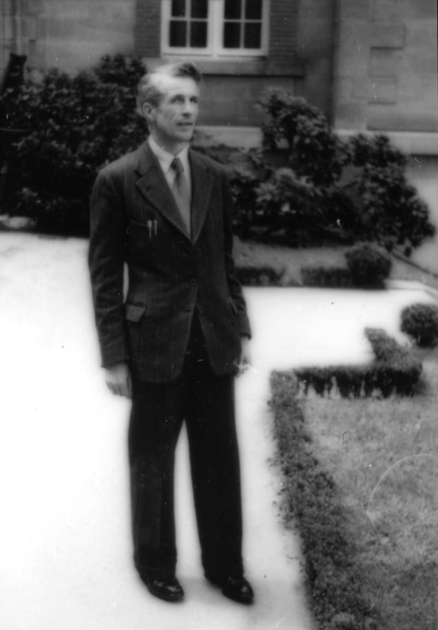 Sort-hvid fotografi af en mand i jakkesæt uden for et stort hus