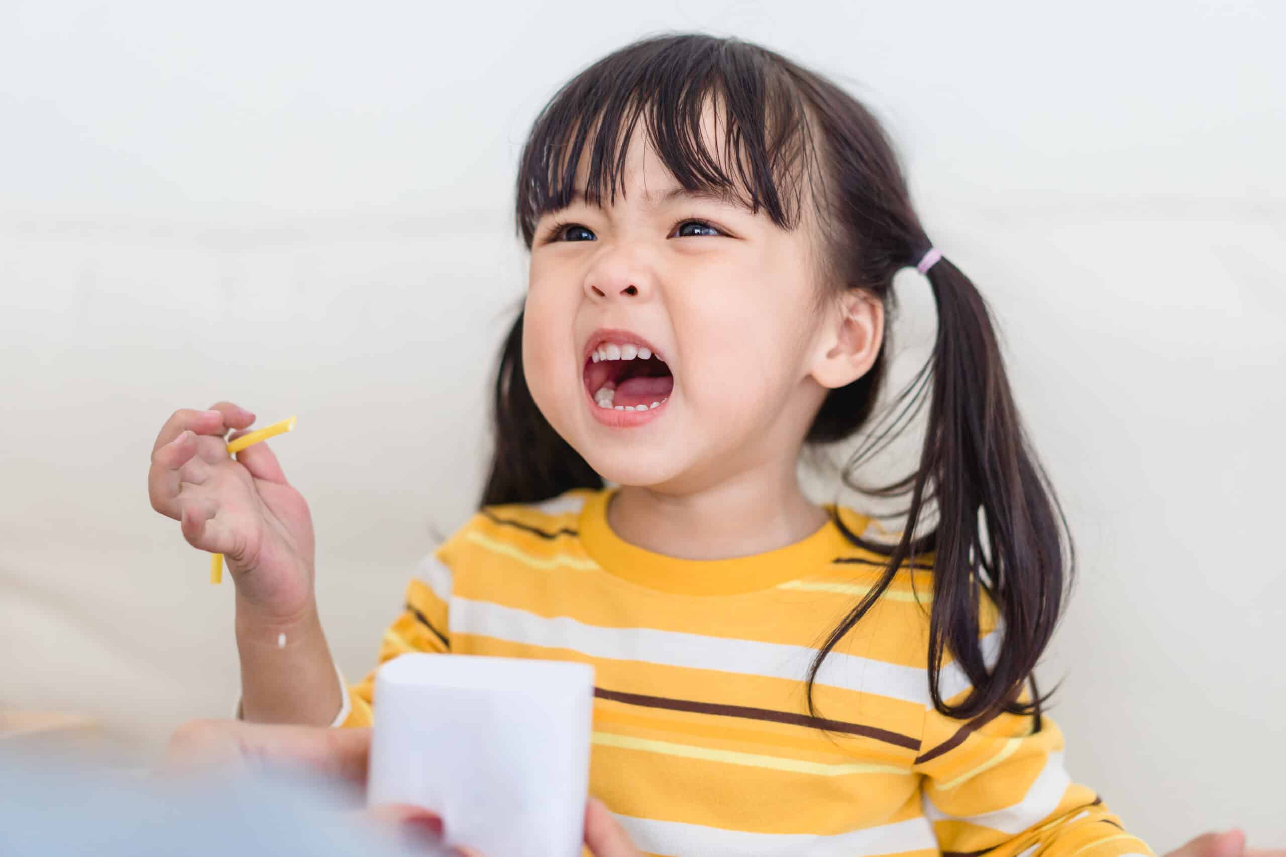A toddler in a yellow shirt complaining (Shutterstock)